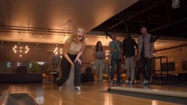 Bowling salonunda bir kadın topu piste atar ve ağır çekimde bir şutu indirir ve zıplayarak neşe içinde dans eder. Arkadaşlar destek olur ve gülümseyerek alkışlarlar. Çok ırklı arkadaşlar birlikte bowling oynuyorlar..