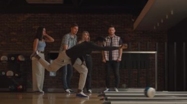Genç siyahi bir adam bowling topuyla son atışı yapıyor ve oyunu farklı uluslardan arkadaşlarının desteği ve neşesiyle kazanıyor. Sevinin ve zaferi kutlayın.