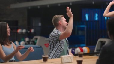 Çok ırklı bir arkadaş grubu bir bowling salonunda aynı masaya oturur ve konuşur. Beş neşeli sarışın kadın sevinçten zıplar ve zaferi kutlar..