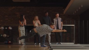 Genç bir adam bowling topuyla son atışı yapıyor ve farklı uluslardan arkadaşlarının desteği ve neşesiyle maçı kazanıyor. Sevinin ve zaferi kutlayın.