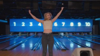 Kafkasyalı genç kadın kameraya bakıp zaferi yavaş çekimde kutluyor. Bowling salonuna atış yapmak için at. Zafer dansı ve mutlulukla zıpla.