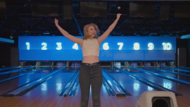 Kavkazská mladá žena Skok šťastně dívá do kamery, oslavovat vítězství ve zpomaleném filmu. Hoď tam bowlingovou dráhu, aby sis zastřílel. Vítězství tančit a skákat štěstím. — Stock video
