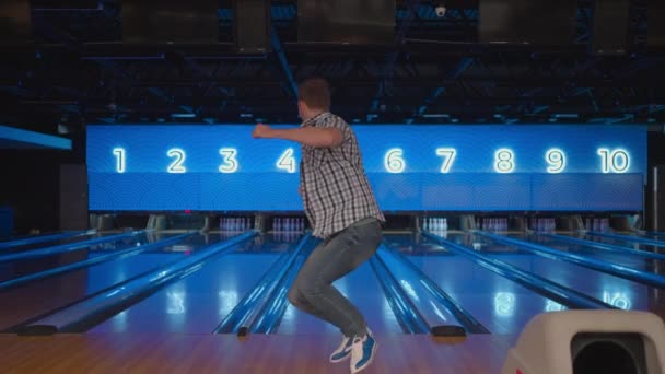 Mladý muž se radostně podívá do kamery a zvolna oslavuje vítězství. Hoď tam bowlingovou dráhu, aby sis zastřílel. Vítězství tančit a skákat štěstím. — Stock video