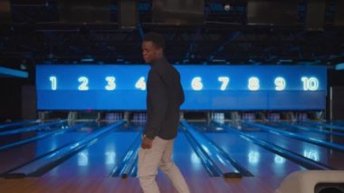 Siyah Afro-Amerikalı adam kameraya bakıp zaferi yavaş çekimde kutluyor. Bowling salonuna atış yapmak için at. Zafer dansı ve mutlulukla zıpla.