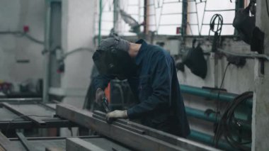 Çalışan bir kaynakçı metal parçalarını gaz veya elektrik kaynaklarıyla yavaş çekimde birbirine bağlar
