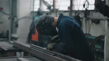 Profesyonel kaynakçı, fabrika, kıvılcım ve elektrikte metal parçalarıyla iş yapıyor. Ağır çekimde sanayi işçisi afişi