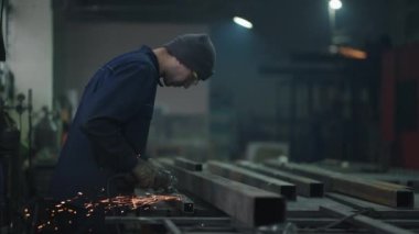 Açı öğütücüyle çeliği kesen ağır bir endüstri işçisi. Ağır endüstri el işçiliği