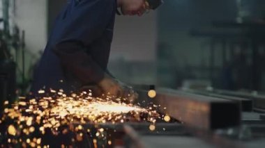 Adam dairesel testere ile çalışıyor. Sıcak metalden kıvılcımlar çıkıyor. Adam çeliğin üzerinde çok çalıştı. Ağır çekim. Çelikle çalışmaktan kıvılcımlar.