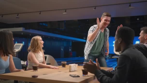 A happy man in a bowling club happily runs to his friends to celebrate the knocked out airstroke. Share the victory with friends. Multi-ethnic group of friends — Stock Video