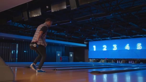 Hvit mann i bowling kaster en ball i sakte film og slår ned noen kjegler. Spille bowling. Kast baller på bowlingklubbens gulv – stockvideo