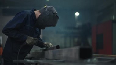 Fabrikadaki maskeli bir kaynakçı tren için bir araba yapmaya çalışıyor. Parçalar birleştiriliyor