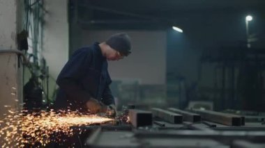 Genel plan: Koruyucu gözlüklü bir adam metal cilalama ve çelik metal yapıları sökme ile çalışır.