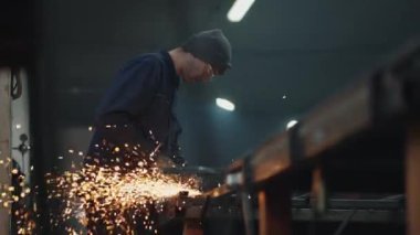 Koruyucu gözlüklü bir adam metal cilalama ve çelik metal yapıları sökme ile çalışır..