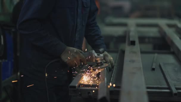 Primer plano: Un hombre con gafas trabaja con pulido de metal y pelado de estructuras metálicas de acero. — Vídeo de stock