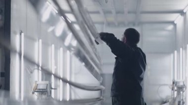 Fabrikadaki resim atölyesinde resim yapmaya hazırlanan bir ressamın portresi. Kompresörden toz ve kir fışkırıyor. Ağır çekim. Barut kaplama hazırlığı