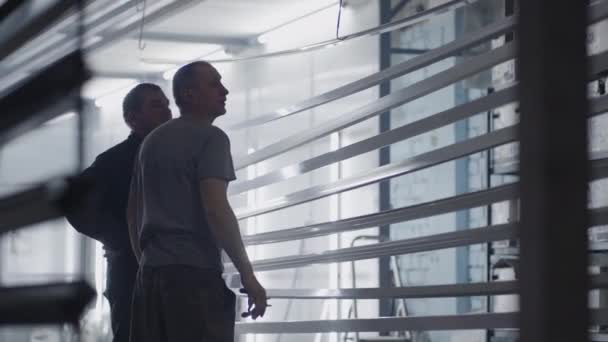 Dos pintores masculinos que trabajan en la fábrica preparan elementos metálicos de acero para pintar fijándolos en suspensiones. Piezas de pintura en la sala de producción. filmación en cámara lenta. — Vídeos de Stock