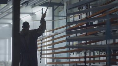 Genel plan. Azıdişi çalışan bir adam fırından parça çıkarır. Çelik metal ürünleri üretimi için fabrika. Boyama atölyesi