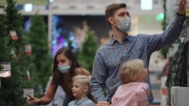 İki çocuklu bir anne ve baba, Noel ağacı oyuncaklarını ve Noel arifesinde salgın ve karantina sırasında ev dekorasyonlarını seçiyorlar. Mağazada tıbbi maskeli bir aile
