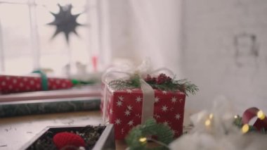 Paketli bir hediye masanın üzerinde duruyor ve kamera masanın etrafında ağır çekimde uçuyor..