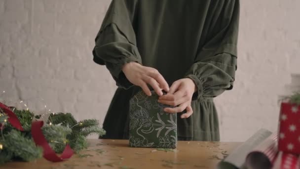 木製のテーブルの上の女性は緑のクリスマスプレゼントを飾る — ストック動画