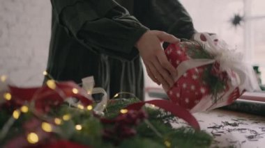 Hediye hazır. Genç ve güzel bir kadın hediye paketi bir Noel hediyesini paketliyor ve dekoratif çevre dostu dekorasyonlarla süslüyor. Tatil sezonu hazırlığı. 