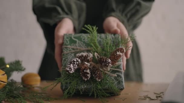 Een kerstcadeau verplaatst een vrouwenhand in de camera. Groen verpakt cadeau vrouw beweegt in de camera na verpakking en versieren — Stockvideo