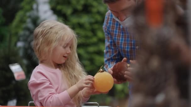 Dad and child choose Christmas toys on the store shelf. Father and little daughter in shopping cart choose Christmas decorations — Stock Footage Dad and child choose Christmas toys on the store shelf. Father and little daughter in shopping cart choose Christmas decorations Video Clip