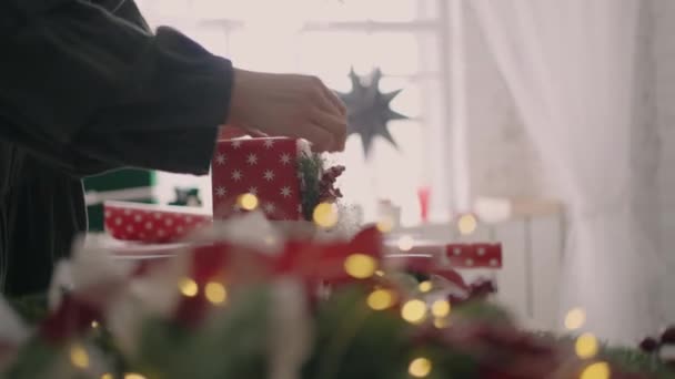 Young beautiful woman gift wrapper wraps up a Christmas gift and decorates with decorative eco-friendly decorations in slow motion — Stock Video