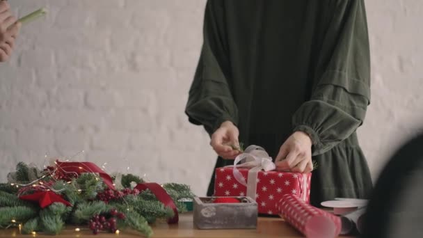 Schnitthände dekorieren verpackte Schachtel mit Schnur. Weibliche Verpackung Karton Geschenkbox auf Holztisch mit verschiedenen dekorativen Artikeln für die Weihnachtsfeier vorbereitet. Detail weibliche Hände binden — Stockvideo