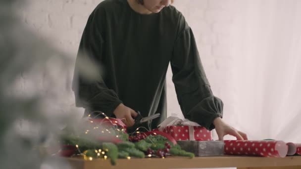 Руки на полях украшают упакованную коробку верёвкой. Женщина упаковки картонные подарочные коробки различные декоративные элементы, подготовленные к празднованию Рождества. Связывающая верёвка женского пола — стоковое видео