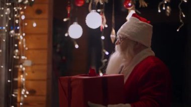 Dışarıda sakallı ve gözlüklü gerçek bir Noel Baba Noel arifesinde evin penceresine bir hediyeyle gelir.