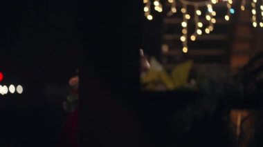 Noel Baba kışın sokakta elinde bir hediye taşır ve kapıya gelir ve çelenkler ve Noel süsleriyle eve girer.