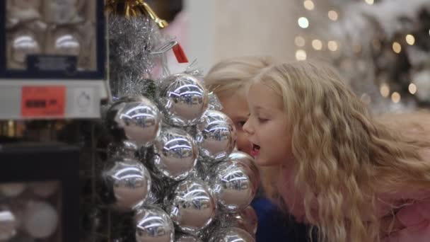 Kinder schwelgen im Laden und machen Gesichter und lachen beim Anblick von Weihnachtskugeln — Stockvideo