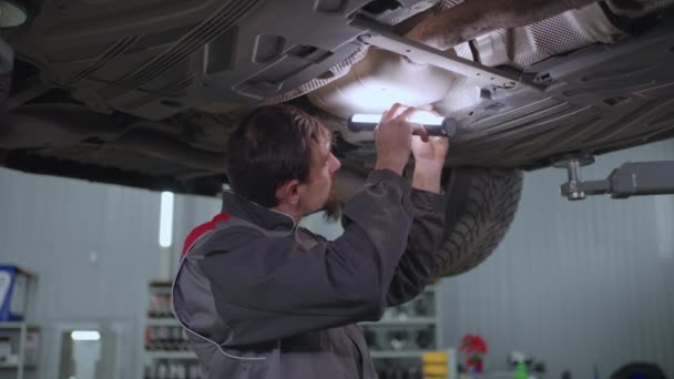 Μηχανικός επισκευάζει ένα αυτοκίνητο που κρέμεται σε έναν ανελκυστήρα — Αρχείο Βίντεο