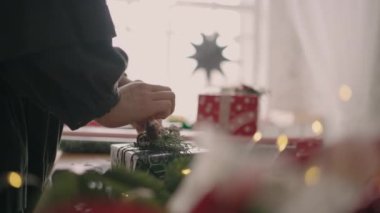 Noel hediyesinin son paketi ahşap bir masa üzerinde ambalaj kağıdı ve çelenklerle.