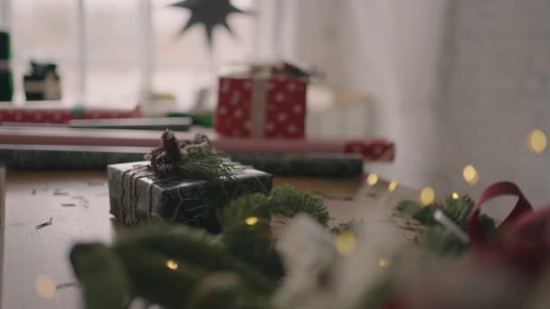 A Christmas present stands on a wooden table with Christmas trees and garlands. Beautiful Christmas gift — Stock Video