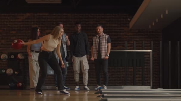 Allmän plan Kvinnliga Bowling Player kastar boll med stöd vänner och röster genom att slå ut en remsa — Stockvideo