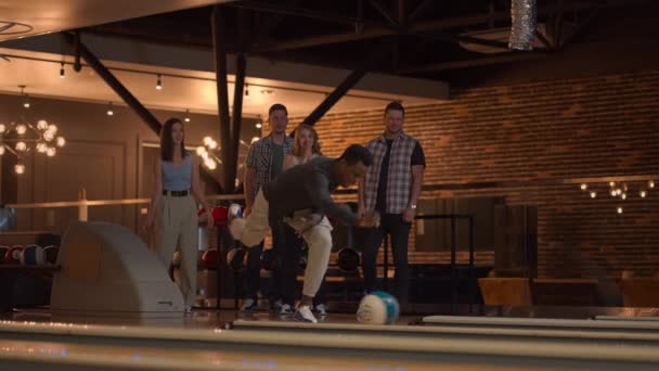 Plan ogólny Czarny Mężczyzna Bowling Player rzuca piłkę ze wsparciem przyjaciół i raduje się znokautując Strip — Wideo stockowe