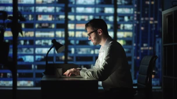 Portrait d'un homme d'affaires réfléchi et prospère travaillant sur un ordinateur portable dans son bureau de la grande ville la nuit. Analyse des données pour la stratégie de commerce électronique — Video
