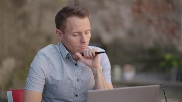 Portrait of a brooding man sitting with a laptop and planning to solve problems and brainstorming — Stock Video