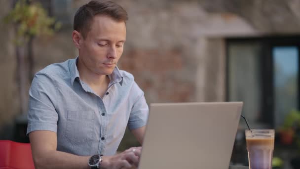 Hübscher freiberuflicher Geschäftsmann mit Brille, der im Café fleißig am Laptop arbeitet. Mann tippt auf Tastatur und sucht im Internet einen neuen Job im Café. Geschäftskonzept — Stockvideo