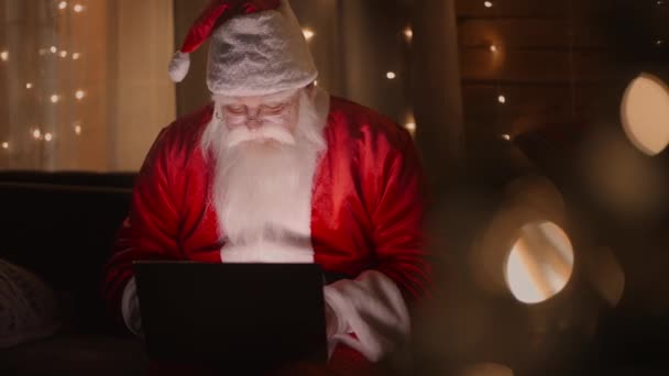 Porträt: Der Weihnachtsmann am Laptop verschickt oder erhält per E-Mail Glückwünsche oder Wünsche für Weihnachten oder Neujahr. — Stockvideo