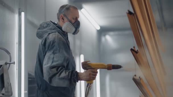 Een man in een beademingsapparaat schildert metaal met een poedermethode. Productie van staal- en metaalconstructies. Schilderij. De schilder werkt met een spuitpistool verf wordt aangebracht — Stockvideo