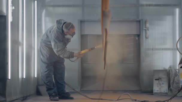 Een man met een beademingsapparaat schildert metaal. Productie van staal- en metaalconstructies. Schilderij. De schilder werkt met een spuitpistool verf wordt aangebracht — Stockvideo