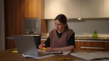 Bilgisayarlı bir masadaki ev ofisinde uzaktan çalışan bir kadının portresi ve bir grafiğe, iş ekonomisti analistine veri notları. Not alır, not alır.