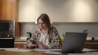 Milenyum kadın çalışanı masa başında oturup bilgisayar işine ara veren bir telefon kurye uygulamasında sohbet ediyor. Genç bayan çalışan yönetici web tarayıcı akıllı telefondan mobil uygulama, evden ofis