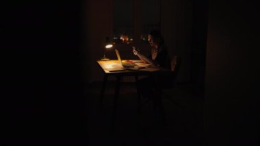 Yorgun, tembel bir kadın çalışanın karanlık bir iş yerinde ofis lambasıyla dizüstü bilgisayar kullanarak uykuya dalması. Aşırı çalışma yorgunluğu. Geç kaldın. Geceleri dizüstü bilgisayar kullanan kadın.