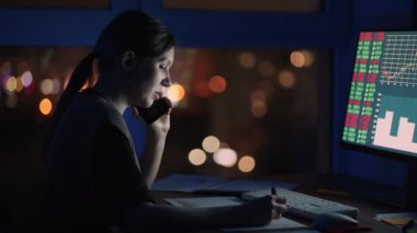 Kadın bir komisyoncu cep telefonuyla konuşuyor. Gerçek zamanlı hisse senetleri, emtialar ve borsa grafikleriyle Bilgisayar üzerinde çalışan bir Mali Analistin Portresi