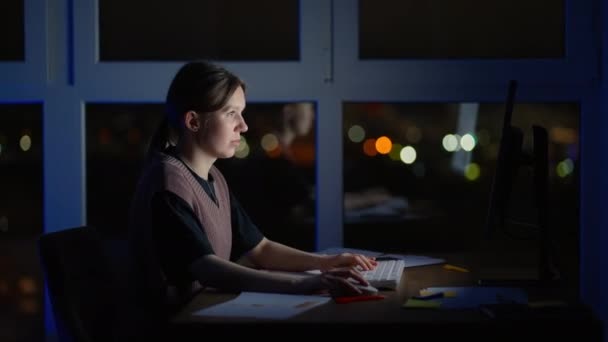 Młoda, dobrze wyglądająca biała kobieta pisząca i pracująca na laptopie jako wolny strzelec siedząc w domu w przytulnym ciemnym salonie z kotem. Wieczorem. Zostań w domu. — Wideo stockowe
