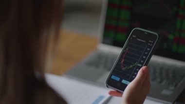 Çizelgeler ve hisse senedi verileriyle yakın plan akıllı telefon ekranı, broket analisti ekrana bakıyor